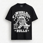A black short-sleeve t-shirt with a white graphic print on the front. The graphic features a bull mascot, the text 'WORLD CHAMPIONS', '1996', 'BACK BACK', and 'BULLS' surrounded by stars.